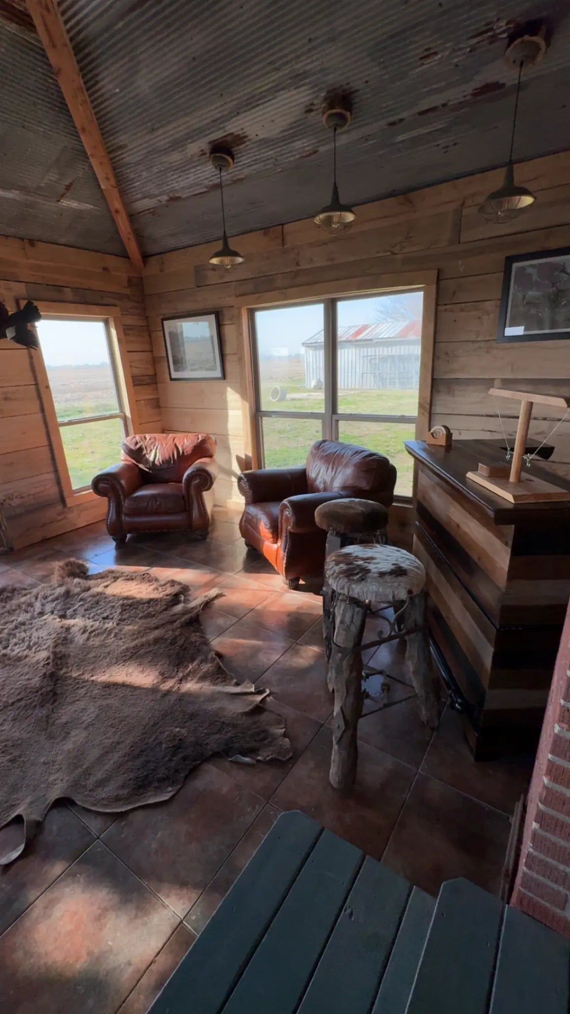 Leather chairs, timber walls, and a corrugated metal ceiling inside The Mallard’s Nest cabin